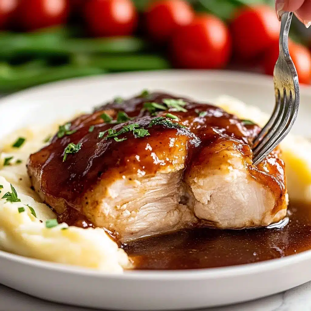 Oven Baked BBQ Chicken, homemade barbecue sauce, juicy baked chicken, easy BBQ chicken recipe, family dinner ideas A close-up view of a white plate with a thick, glossy dark brown sauce-covered piece of cooked chicken with a tender, white inside, placed over a creamy textured layer of mashed potatoes that have a pale yellow color, next to blurred background of bright red cherry tomatoes with green stems and green beans, a woman's hand holds a fork piercing a piece of chicken on the right edge of the plate; the sauce glistens and small green herb pieces are sprinkled on top of the chicken, all set on a white marbled surface,